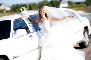 young bride standing beside a limousine